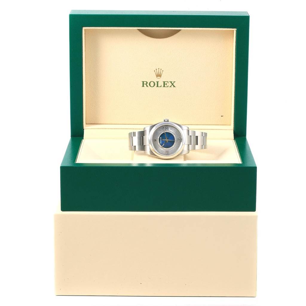 The Rolex Oyster Perpetual 116000 Men
s Stainless Steel Silver Dial 116000 Men
s Stainless Steel Silver Dial watch is shown front-facing in its green and beige display box.