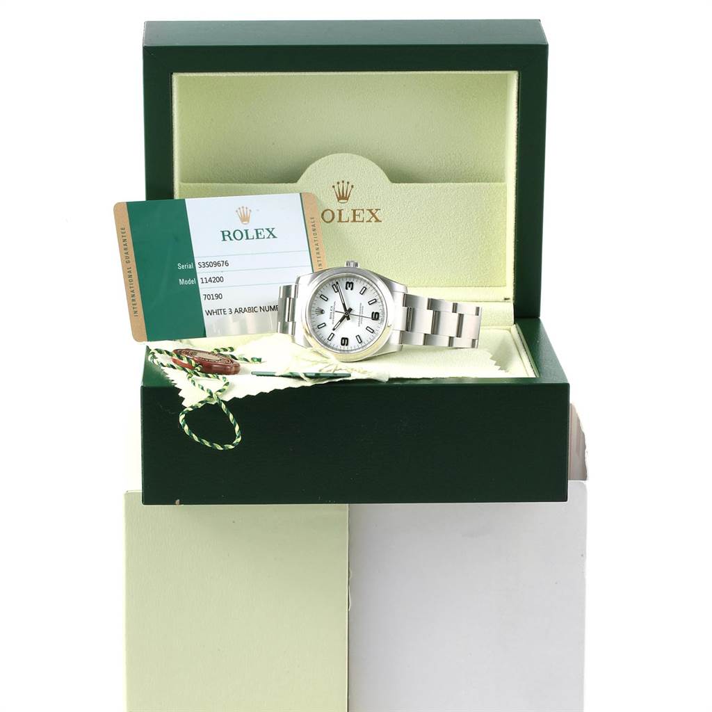 The image shows a Rolex Oyster Perpetual 114200 Men
s Stainless Steel White Dial 114200 Men
s Stainless Steel White Dial watch, displayed in an open box with accompanying documentation and tags.