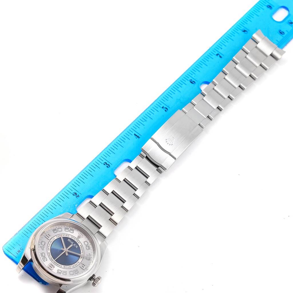 This image shows an overhead view of a Rolex Oyster Perpetual 116000 Men
s Stainless Steel Silver Dial 116000 Men
s Stainless Steel Silver Dial watch, highlighting the bracelet and partial dial next to a blue ruler for scale.