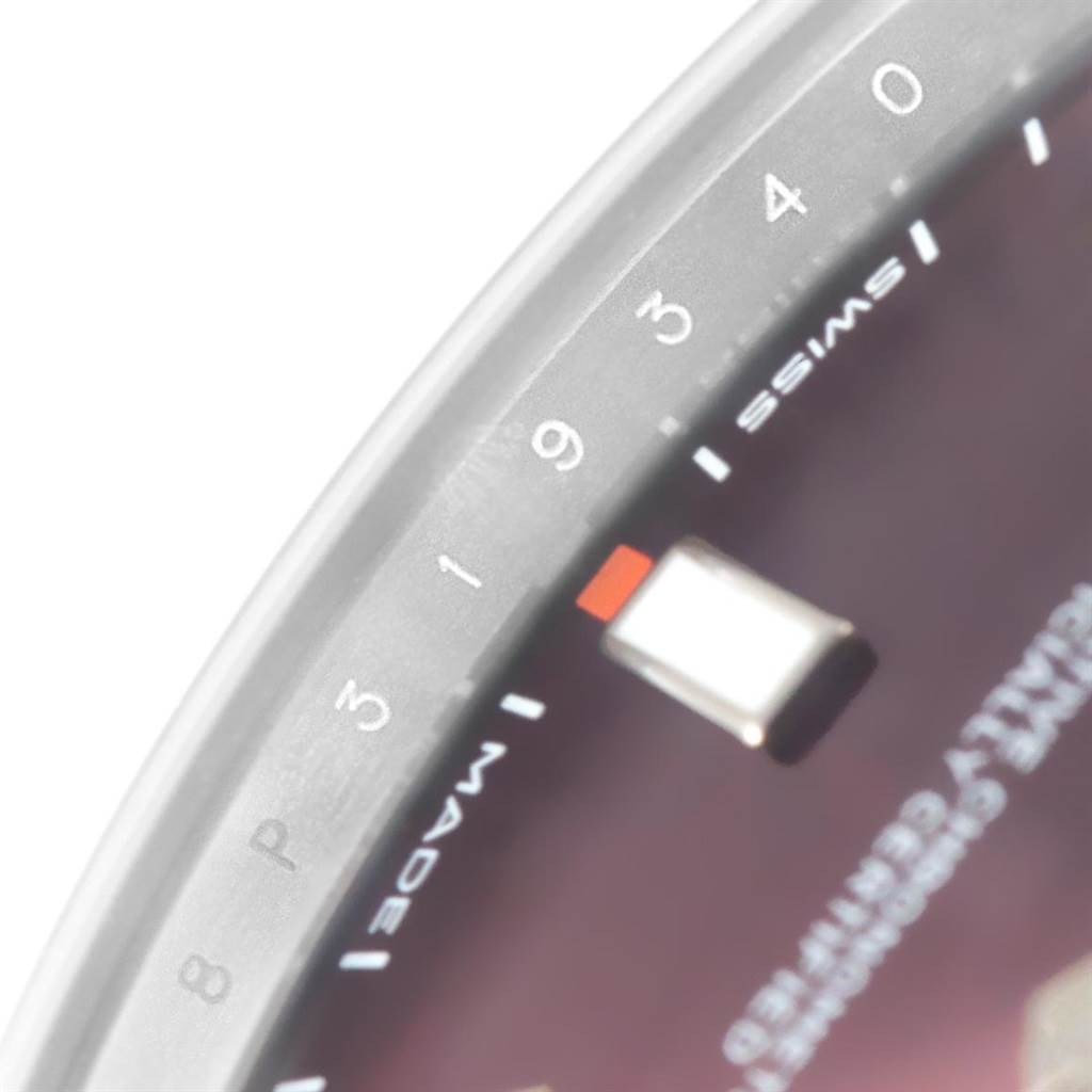 This image shows a close-up of the dial and part of the bezel of a Rolex Oyster Perpetual 114300 Stainless Steel Burgundy Dial 114300 Stainless Steel Burgundy Dial watch.