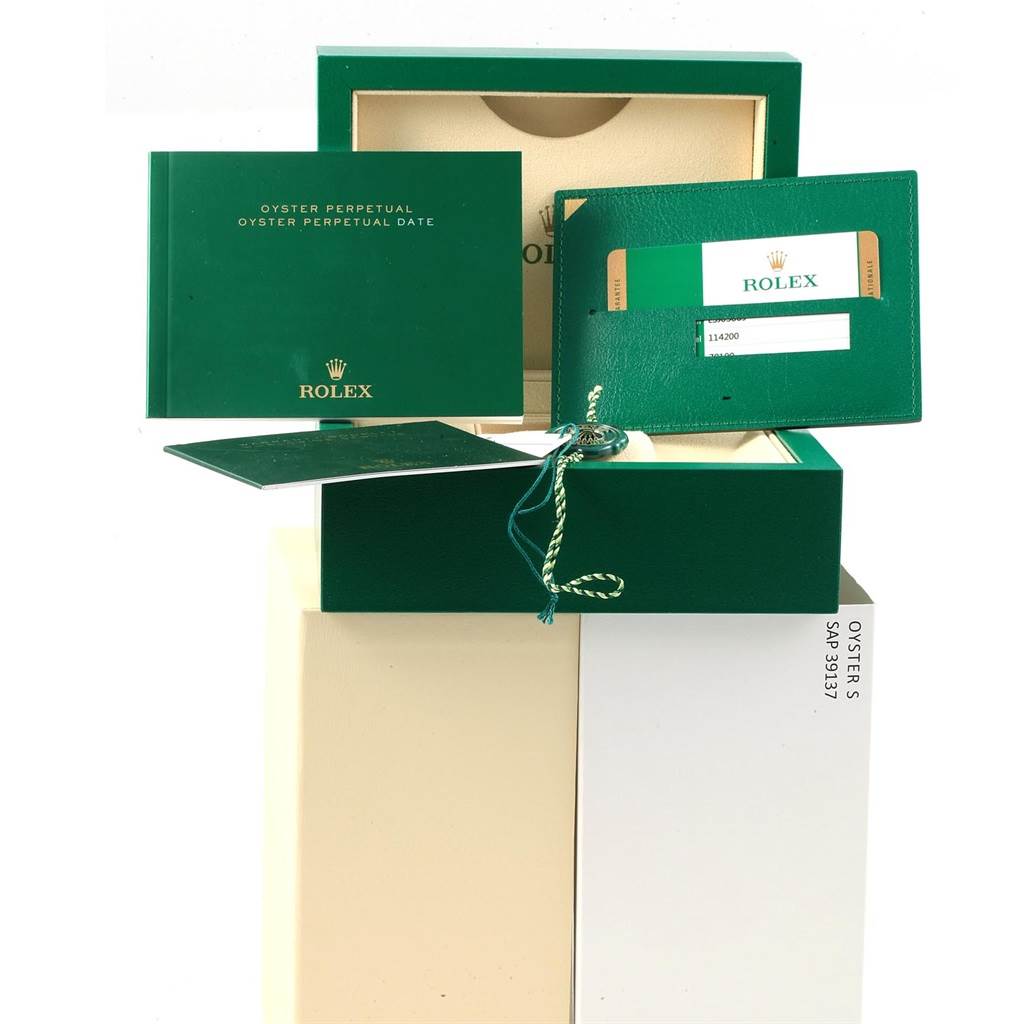 The image shows the packaging, booklet, card holder, and tags for the Rolex Oyster Perpetual 114200 Stainless Steel Champagne Dial 114200 Stainless Steel Champagne Dial watch.