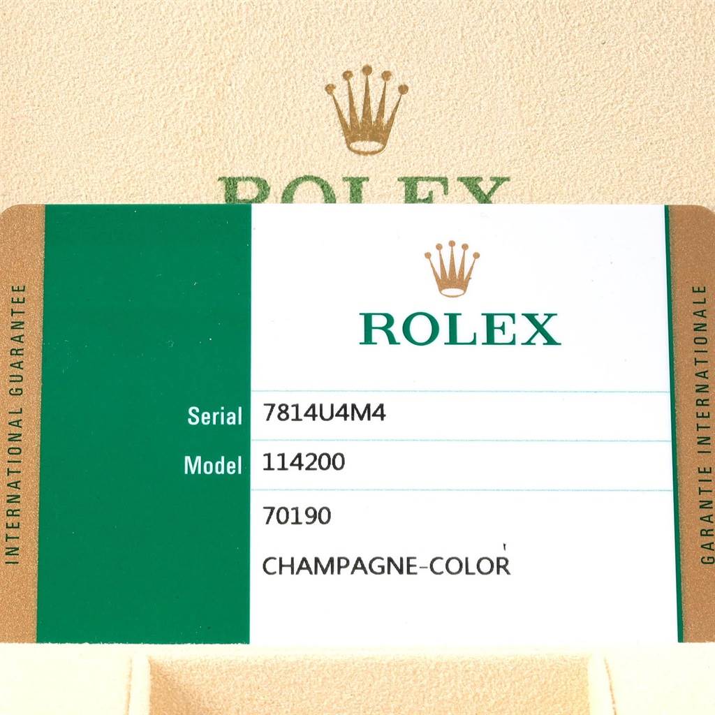 The image shows a Rolex guarantee card for an Oyster Perpetual model 114200, indicating the serial number and champagne-colored dial.