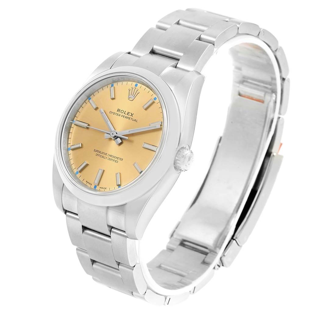 The Rolex Oyster Perpetual 114200 Stainless Steel Champagne Dial 114200 Stainless Steel Champagne Dial watch is shown at a three-quarter angle, displaying the face, crown, and metal bracelet.