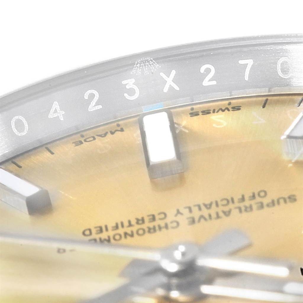 This close-up angle shows the dial, bezel, and part of the text on the face of the Rolex Oyster Perpetual 114200 Men's Stainless Steel Champagne Dial 114200 Men's Stainless Steel Champagne Dial watch.