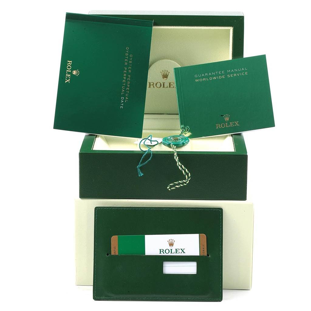 The image shows the accessories of a Rolex Oyster Perpetual 114200 Men's Stainless Steel Champagne Dial 114200 Men's Stainless Steel Champagne Dial watch, including the box, manuals, and warranty card.