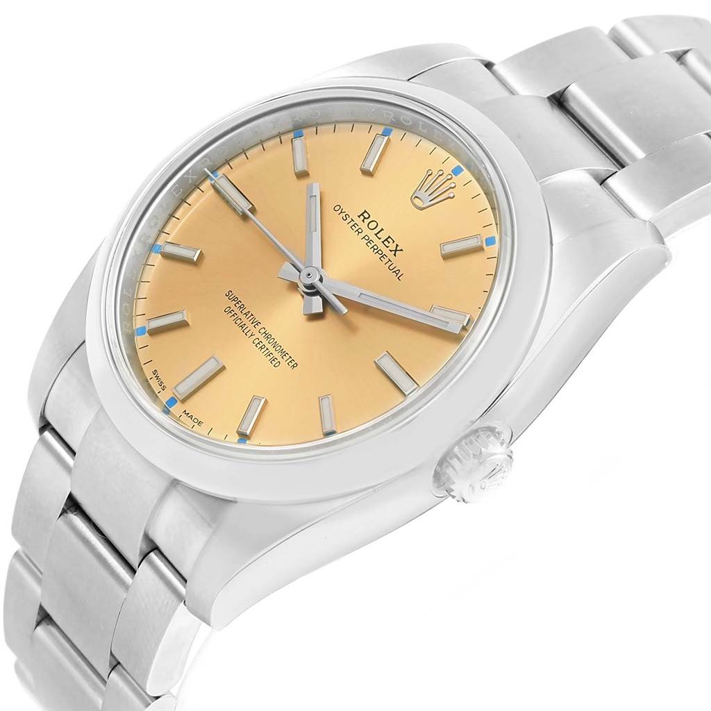 The image shows an angled view of a Rolex Oyster Perpetual 114200 Men's Stainless Steel Champagne Dial 114200 Men's Stainless Steel Champagne Dial watch highlighting its dial, case, and part of the bracelet.