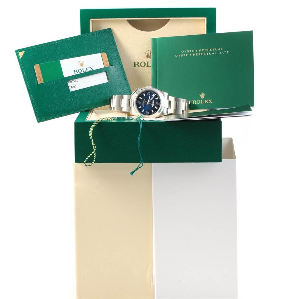 The image shows a Rolex Oyster Perpetual 114200 Men's Stainless Steel Blue Dial 114200 Men's Stainless Steel Blue Dial watch, box, certificate card, and warranty booklet from a front angle.