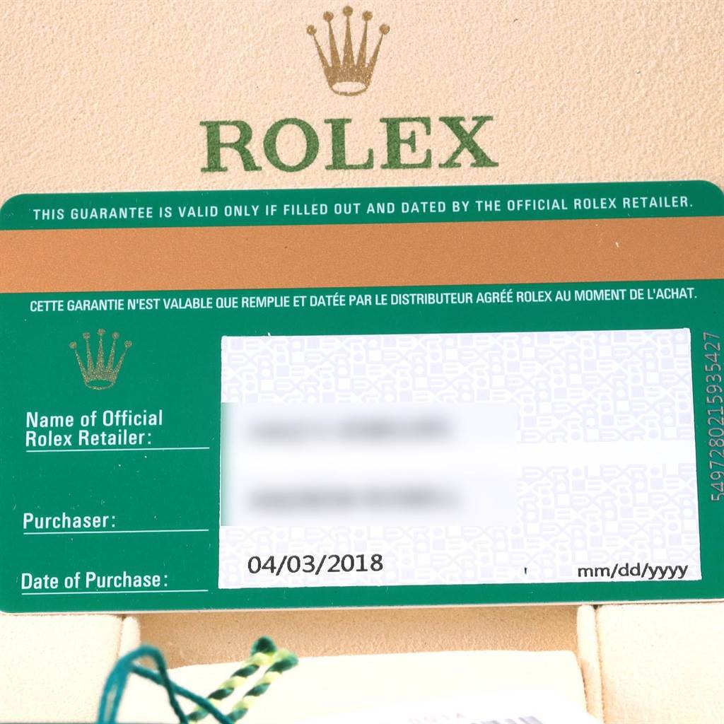 The image shows a close-up of the warranty card and box of a Rolex Oyster Perpetual 114200 Men's Stainless Steel Blue Dial 114200 Men's Stainless Steel Blue Dial watch.