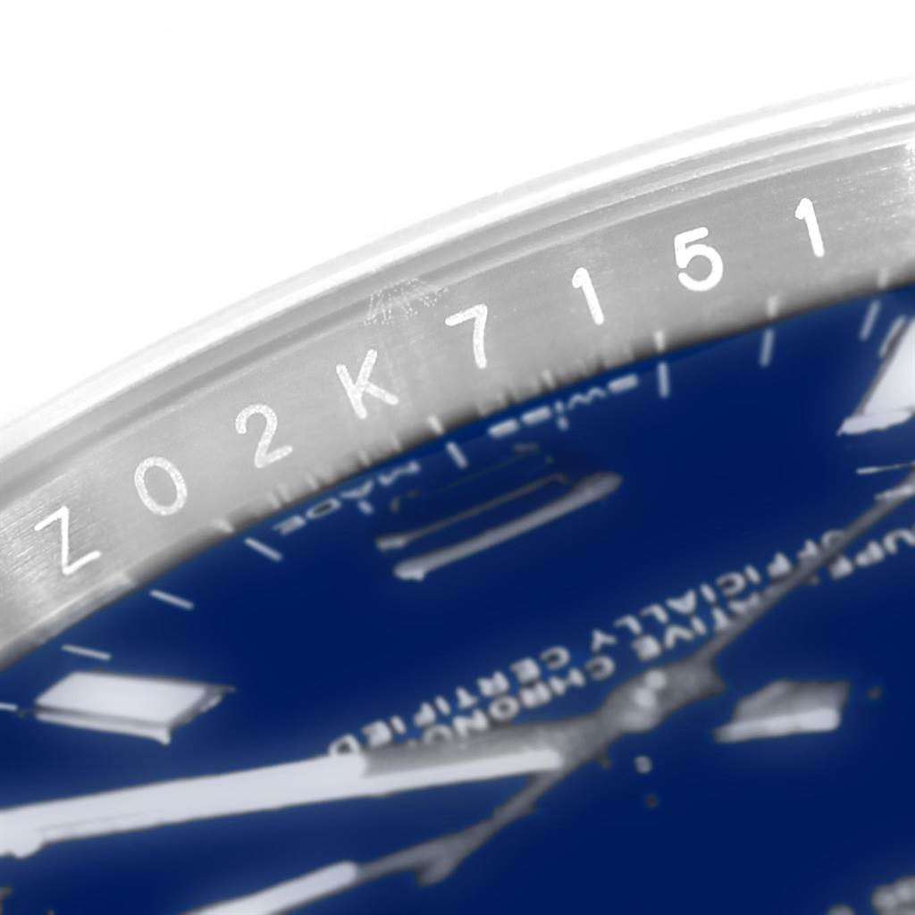 The close-up angle shows the case and part of the dial of a Rolex Oyster Perpetual 114200 Men's Stainless Steel Blue Dial 114200 Men's Stainless Steel Blue Dial watch, featuring a serial number.