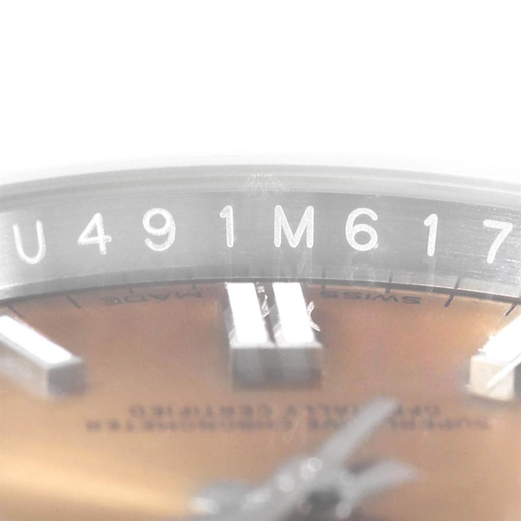 The close-up image shows part of the dial, hour markers, and serial number of a Rolex Oyster Perpetual 116000 Men's Stainless Steel Champagne Dial 116000 Men's Stainless Steel Champagne Dial watch.