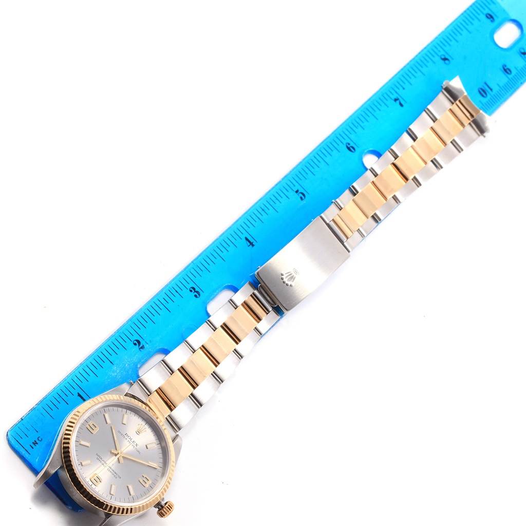 The Rolex Oyster Perpetual 14233 Men's Steel and Gold (two tone) Grey Dial 14233 Men's Steel and Gold (two tone) Grey Dial watch is shown laid flat with a blue ruler, displaying its face, bracelet, and clasp.