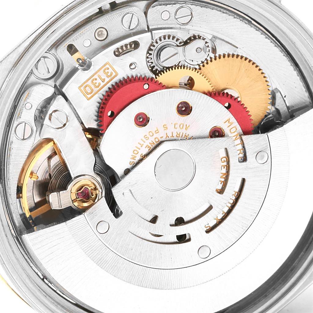 An Oyster Perpetual Rolex watch movement is shown from a close-up, showcasing its intricate gears and internal mechanisms.
