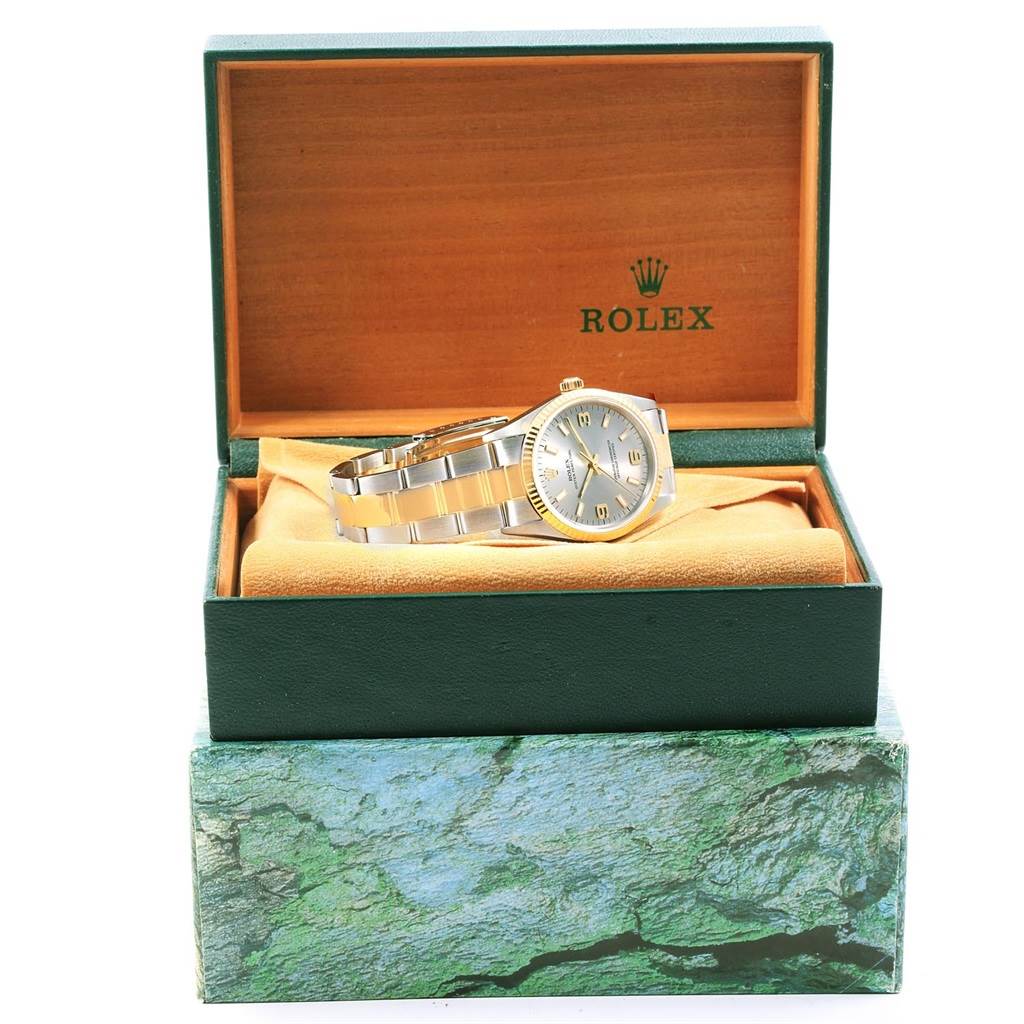 This Oyster Perpetual Rolex watch is displayed at an angle inside its open green and orange box.