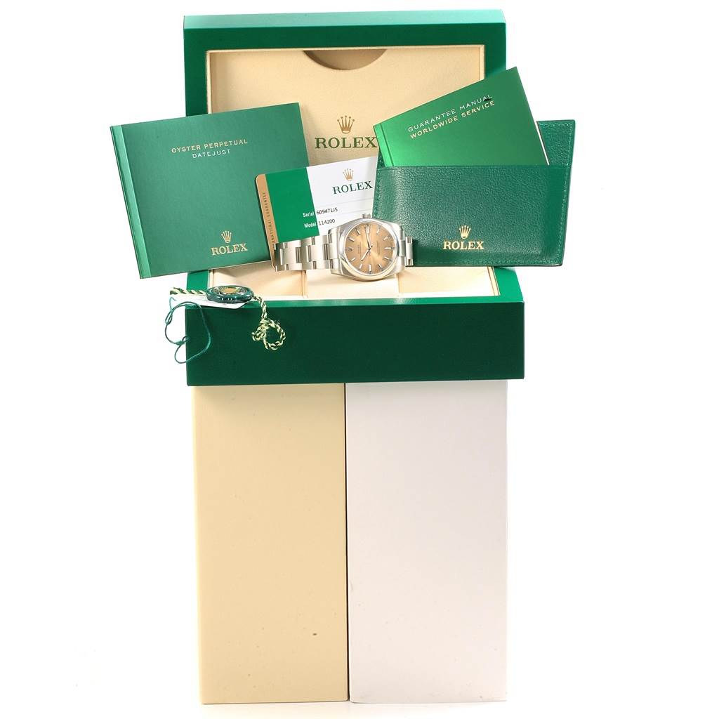This image shows a Rolex Oyster Perpetual 60947155 Stainless Steel Champagne Dial 60947155 Stainless Steel Champagne Dial watch and its accessories, including manuals and warranty card, viewed from the front.