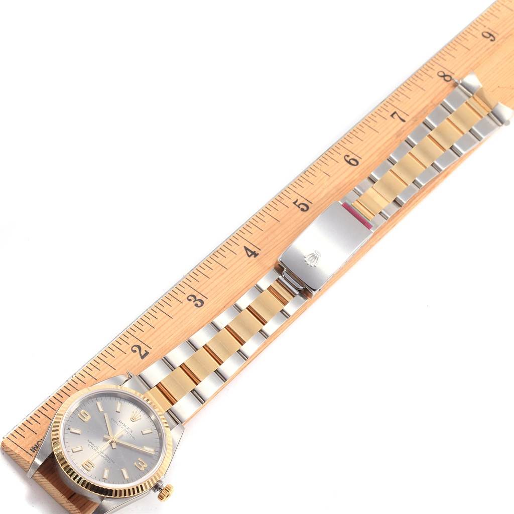 The image shows an overhead view of a Rolex Oyster Perpetual 14233 Men's Steel and Gold (two tone) Grey Dial 14233 Men's Steel and Gold (two tone) Grey Dial watch with a ruler alongside, highlighting its dial and bracelet.