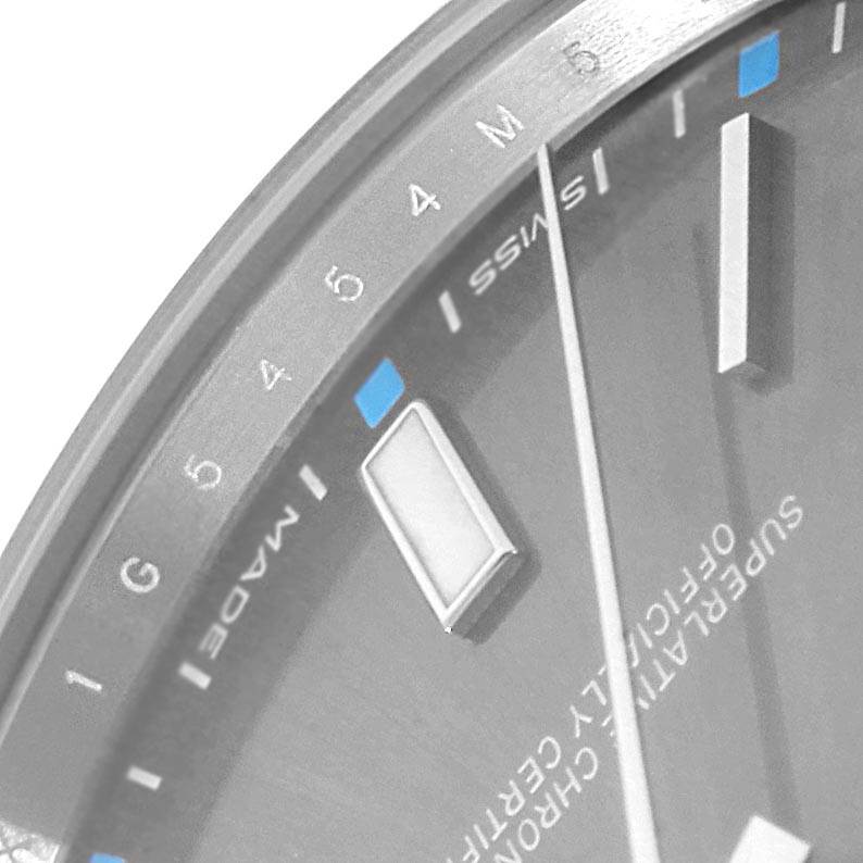 This image shows a close-up of the dial and bezel of a Rolex Oyster Perpetual 114300 Men's Stainless Steel Grey Dial 114300 Men's Stainless Steel Grey Dial, highlighting markers and text.