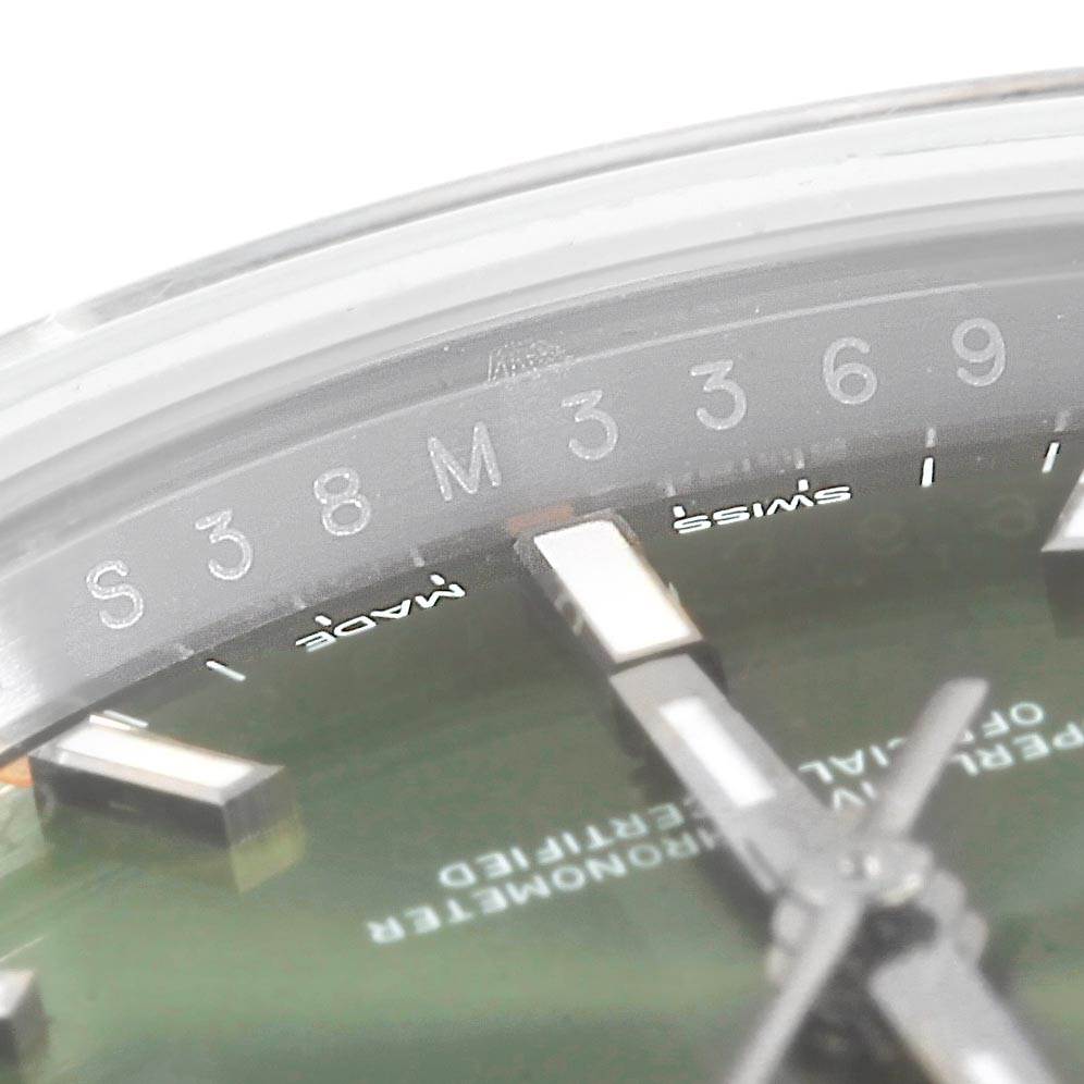 This close-up image shows part of the dial, hands, and the inside of the bezel of a Rolex Oyster Perpetual 114200 Men's Stainless Steel Green Dial 114200 Men's Stainless Steel Green Dial watch.