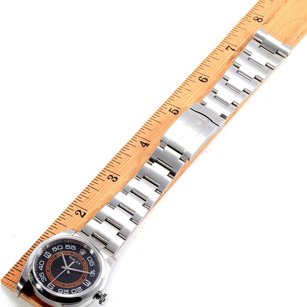 The image shows a top-down view of the Rolex Oyster Perpetual 116000 Men
s Stainless Steel Black Dial 116000 Men
s Stainless Steel Black Dial watch with the bezel, dial, bracelet, and clasp partially measured by a ruler.