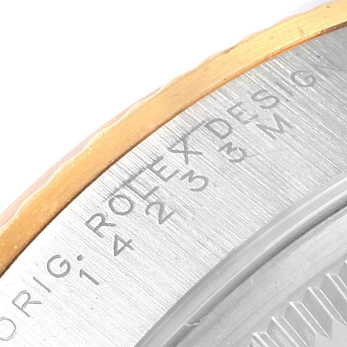 This close-up image of a Rolex Oyster Perpetual 14233 Men
s Steel and Gold (two tone) Grey Dial 14233 Men
s Steel and Gold (two tone) Grey Dial watch shows the engraved text on the case back and part of the gold and steel bezel.