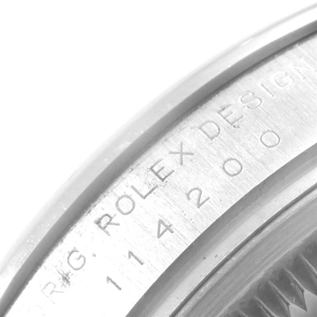This image shows a close-up of the bezel's edge on a Rolex Oyster Perpetual 114200 Men's Stainless Steel Silver Dial 114200 Men's Stainless Steel Silver Dial, highlighting the engraved text.
