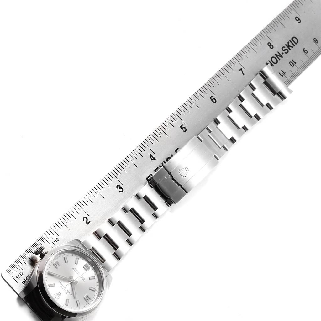 The image shows a Rolex Oyster Perpetual 114200 Men's Stainless Steel Silver Dial 114200 Men's Stainless Steel Silver Dial watch placed diagonally with a ruler measuring its stainless steel bracelet.