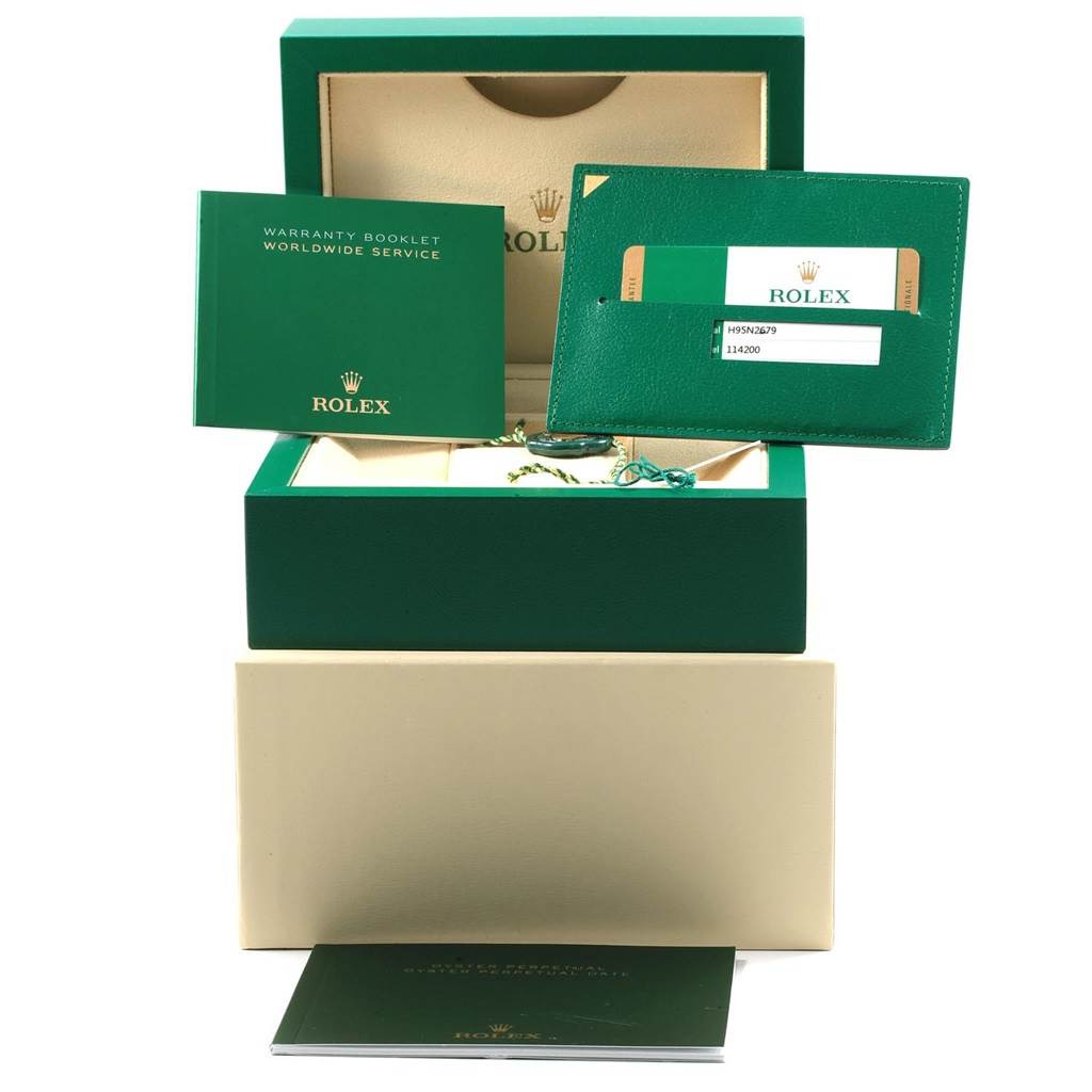 The image shows the packaging and accessories for a Rolex Oyster Perpetual 114200 Men's Stainless Steel Silver Dial 114200 Men's Stainless Steel Silver Dial, including the box, warranty booklet, and card holder.