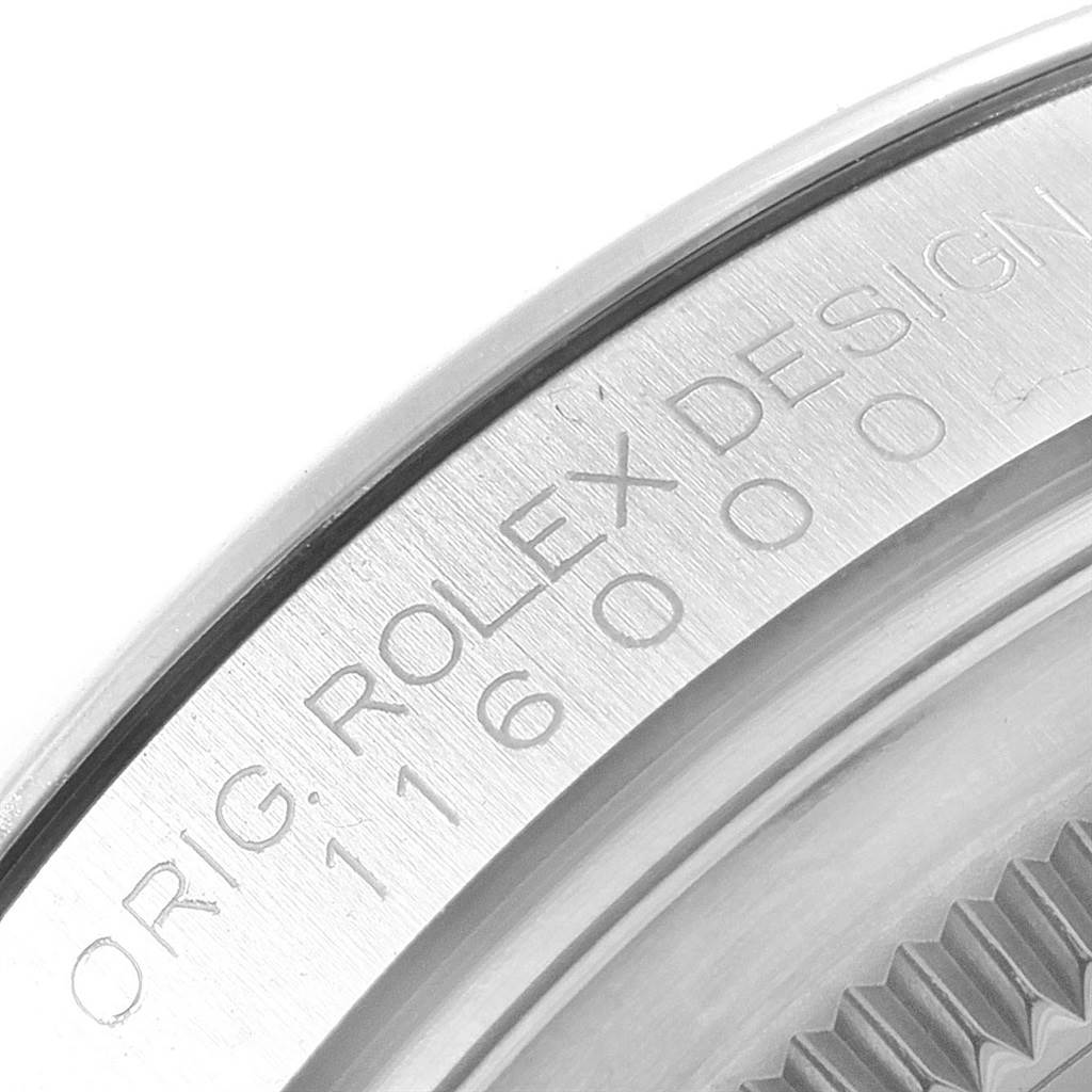 This image shows a close-up of the edge of a Rolex Oyster Perpetual 116000 Men's Stainless Steel Champagne Dial 116000 Men's Stainless Steel Champagne Dial watch, highlighting the engraved model number and branding.