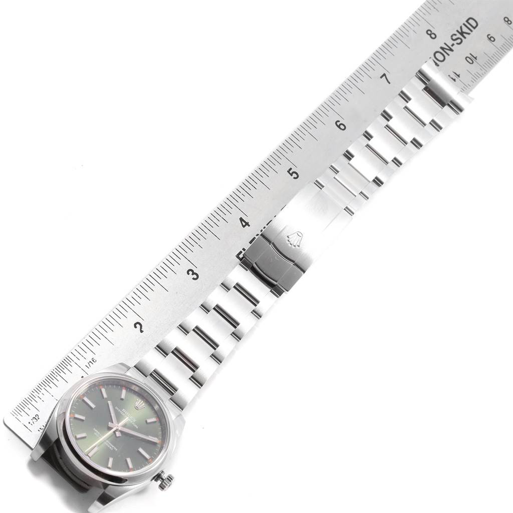 The image shows a Rolex Oyster Perpetual 114200 Men
s Stainless Steel Green Dial 114200 Men
s Stainless Steel Green Dial watch lying flat next to a ruler, showcasing the length and bracelet.