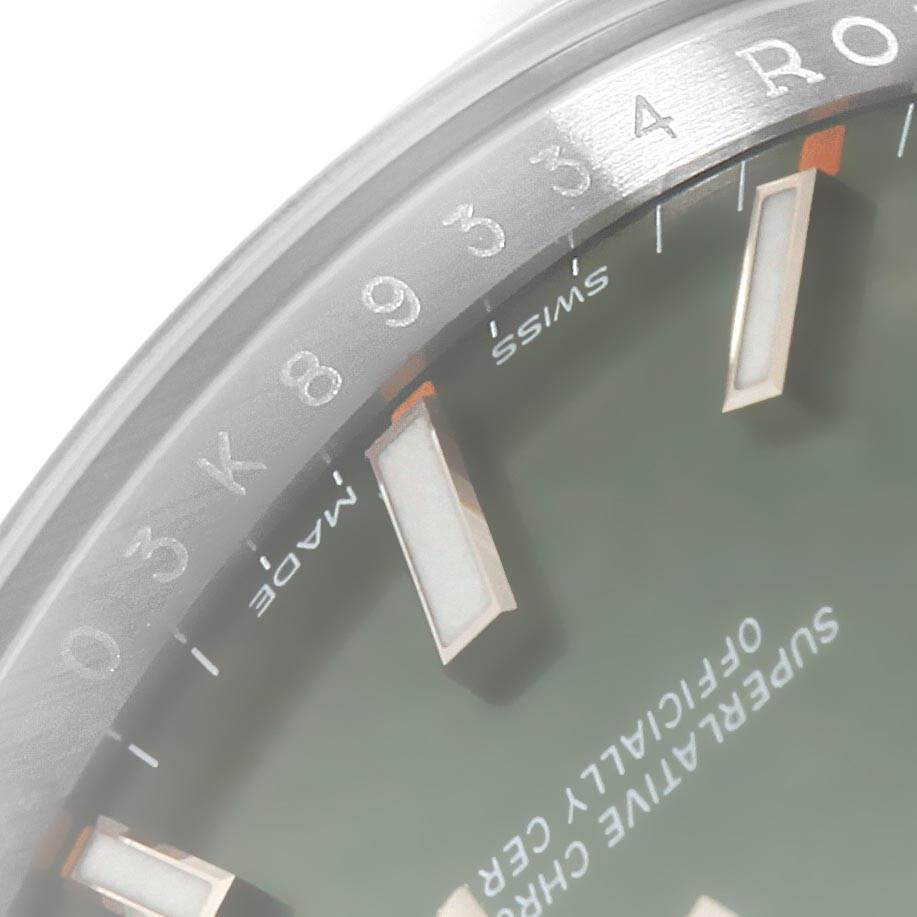 This image shows a close-up of the dial and part of the bezel of a Rolex Oyster Perpetual 114200 Men
s Stainless Steel Green Dial 114200 Men
s Stainless Steel Green Dial watch.