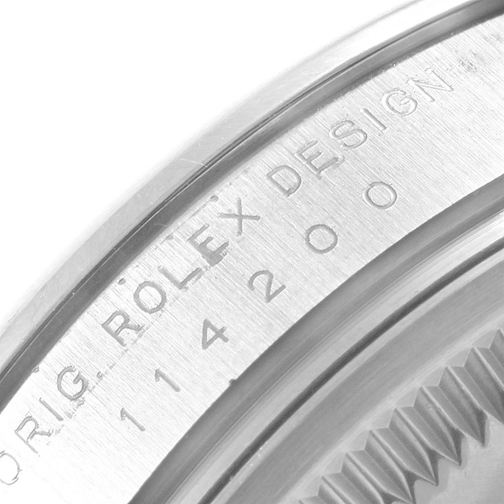 This close-up image shows the side of the casing with the engraved "Rolex Design" and the model number of the Rolex Oyster Perpetual 114200 Stainless Steel Burgundy Dial 114200 Stainless Steel Burgundy Dial watch.