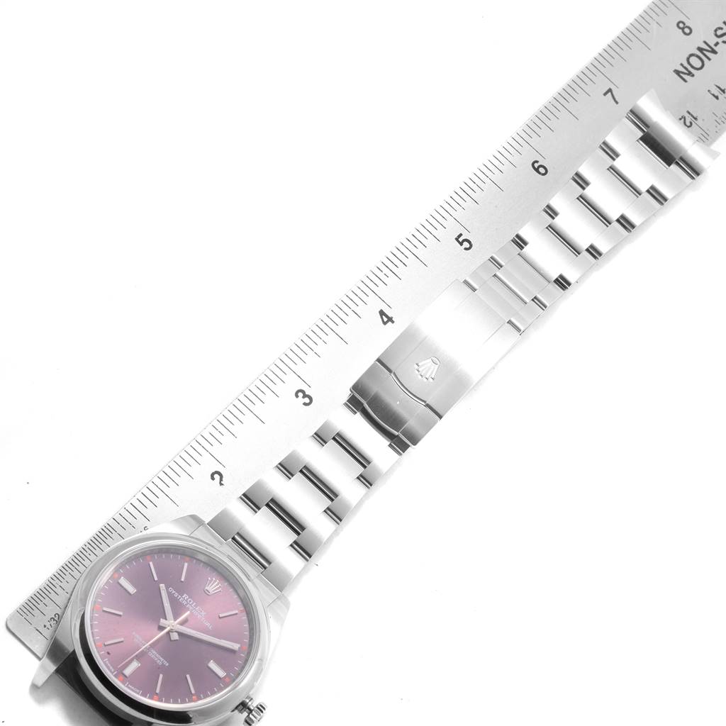 This image shows a side angle view of a Rolex Oyster Perpetual 114300 Men's Stainless Steel Burgundy Dial 114300 Men's Stainless Steel Burgundy Dial watch, featuring the dial, case, and bracelet with a ruler for scale.
