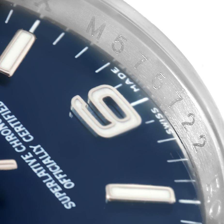 This close-up angle of a Rolex Oyster Perpetual 116000 Men's Stainless Steel Blue Dial 116000 Men's Stainless Steel Blue Dial watch shows part of the dial, indices, and the engraved bezel.