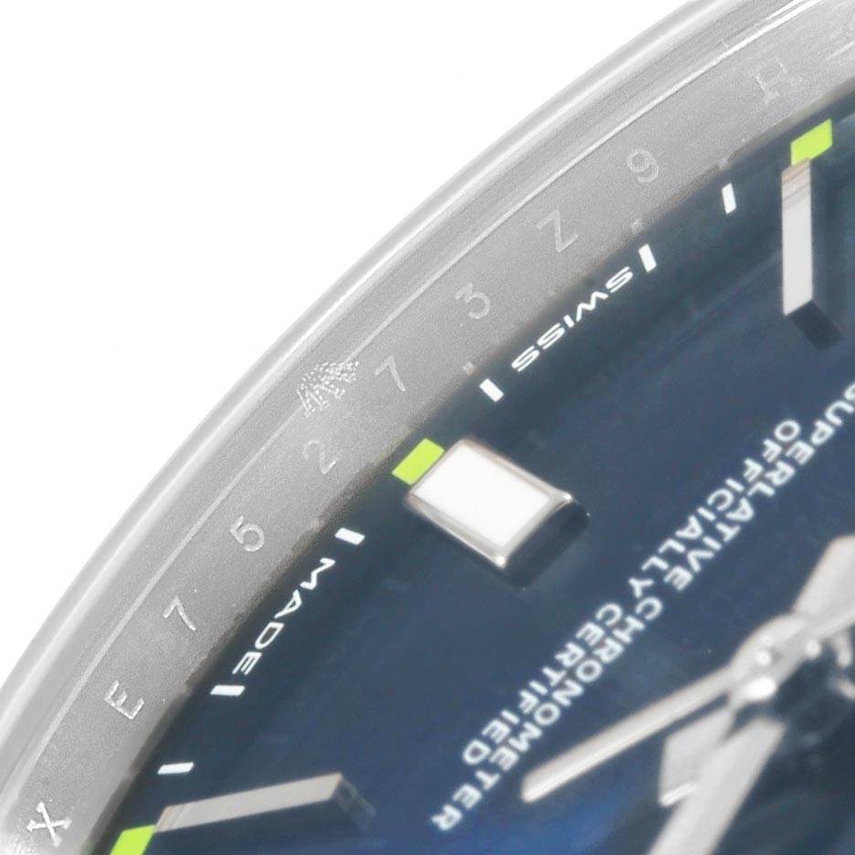 This image shows a close-up of the dial and bezel of a Rolex Oyster Perpetual 114300 Men
s Stainless Steel Blue Dial 114300 Men
s Stainless Steel Blue Dial watch, highlighting indices and text.