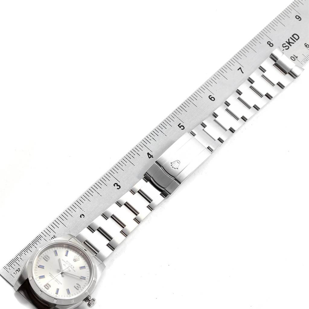 The image shows a Rolex Oyster Perpetual 114210 Men
s Stainless Steel Silver Dial 114210 Men
s Stainless Steel Silver Dial watch laid horizontally alongside a ruler, highlighting the bracelet and clasp.