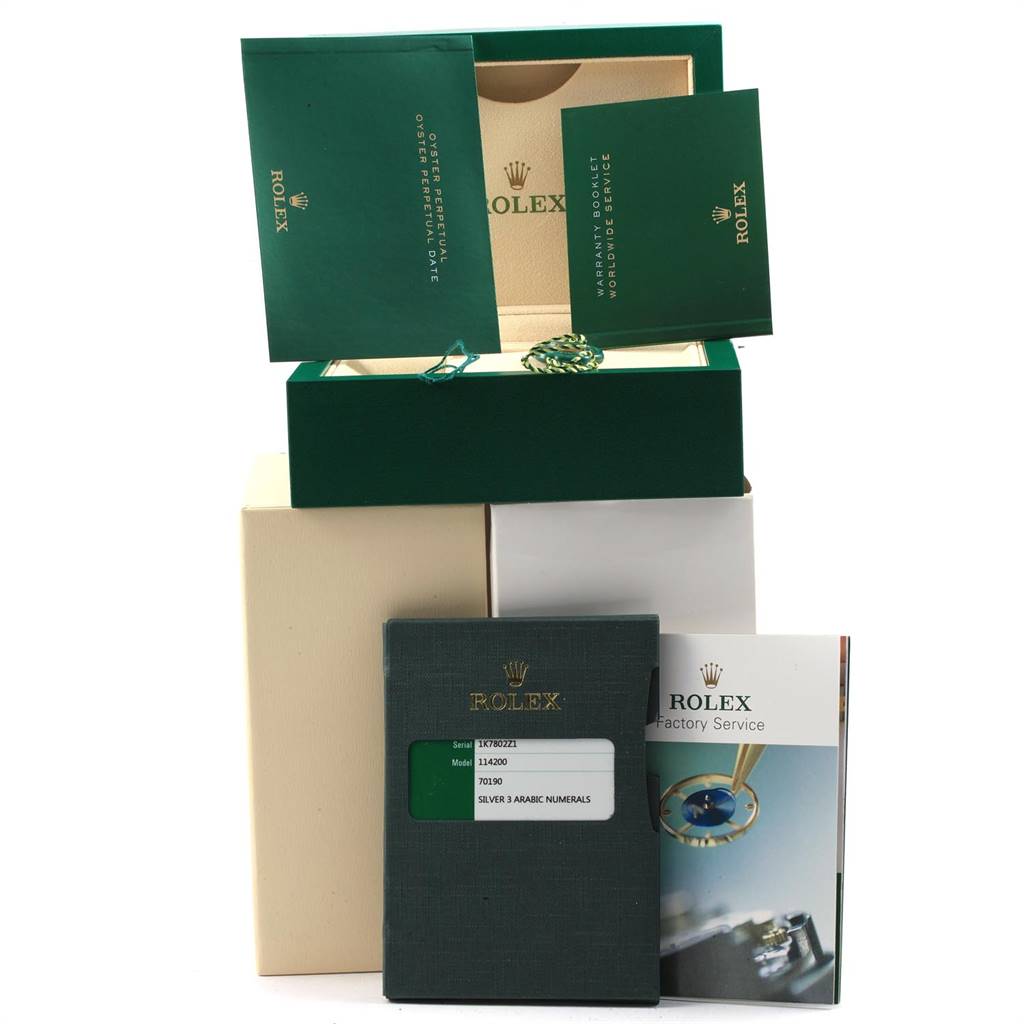 The image shows the packaging, warranty booklet, and manual for a Rolex Oyster Perpetual 114200 Men's Stainless Steel Silver Dial 114200 Men's Stainless Steel Silver Dial model.
