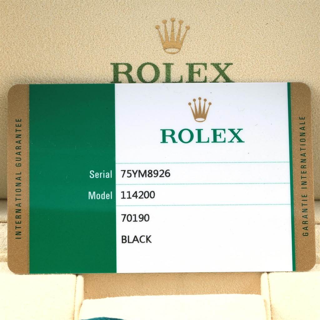 The image shows a warranty card for the Rolex Oyster Perpetual 114200 Men's Stainless Steel Black Dial 114200 Men's Stainless Steel Black Dial model 114200, displaying the serial number and color details.