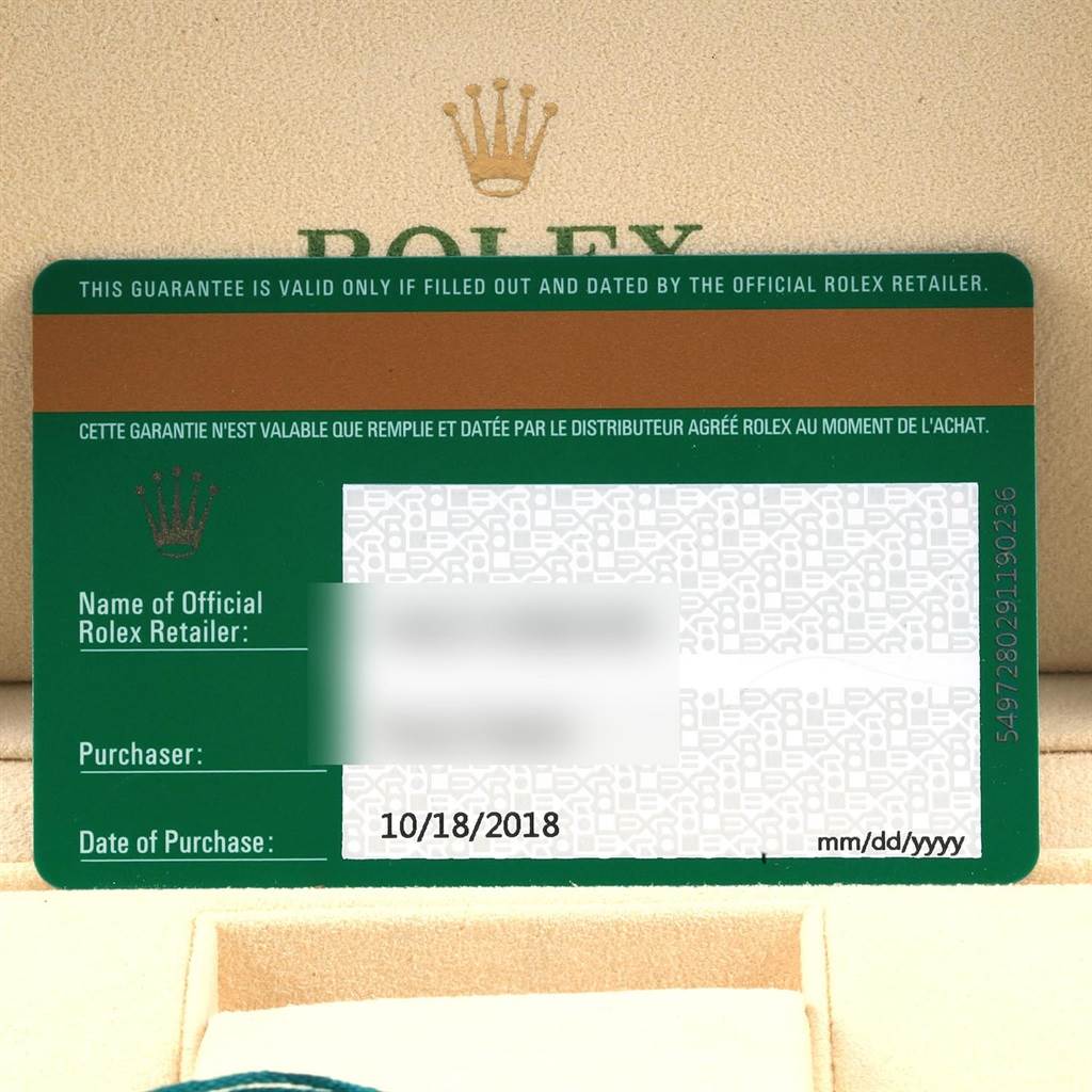 The image shows the warranty card for an Oyster Perpetual model by Rolex, along with parts of the watch's packaging.