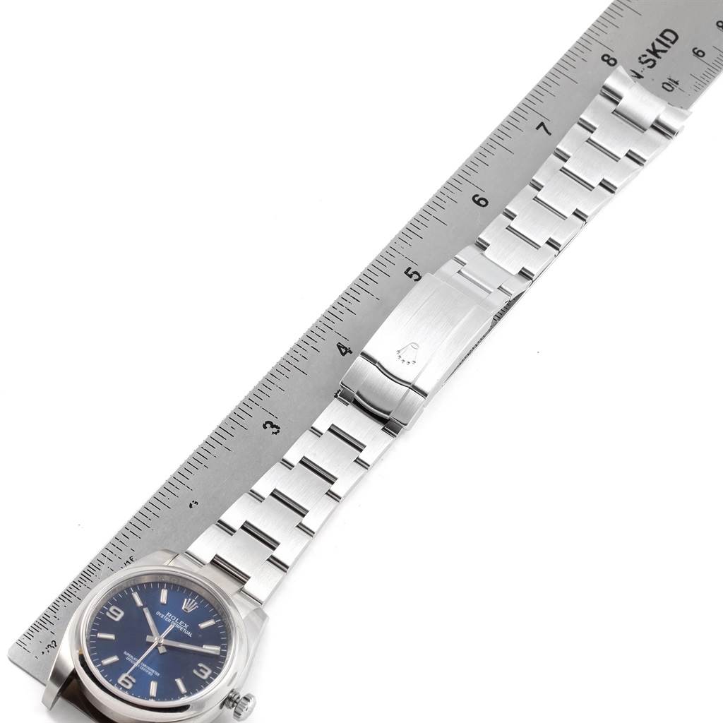 This image shows a Rolex Oyster Perpetual 116000 Men
s Stainless Steel Blue Dial 116000 Men
s Stainless Steel Blue Dial watch with a ruler measuring its metal bracelet.