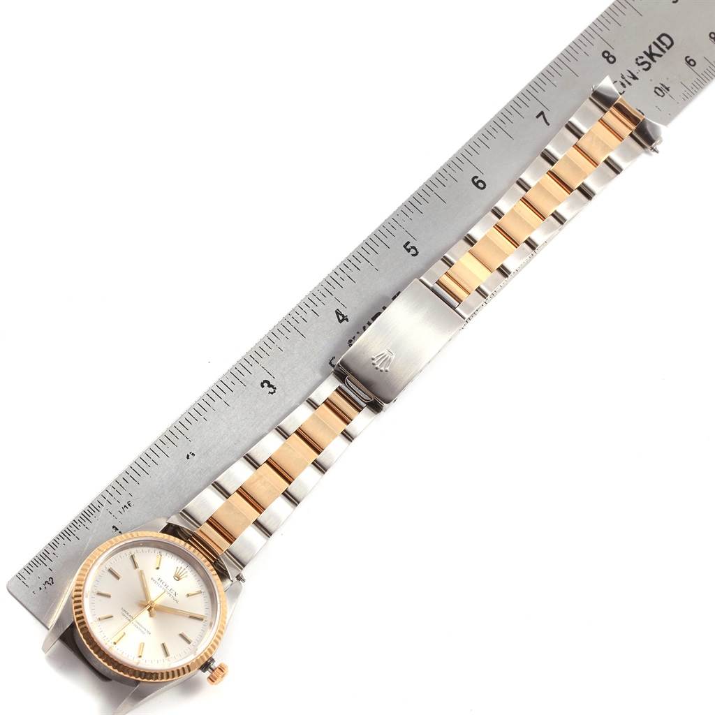 The Rolex Oyster Perpetual 14233 Men's Steel and Gold (two tone) Silver Dial 14233 Men's Steel and Gold (two tone) Silver Dial watch is shown laid flat, with a focus on the dial, bracelet, and clasp next to a ruler for scale.