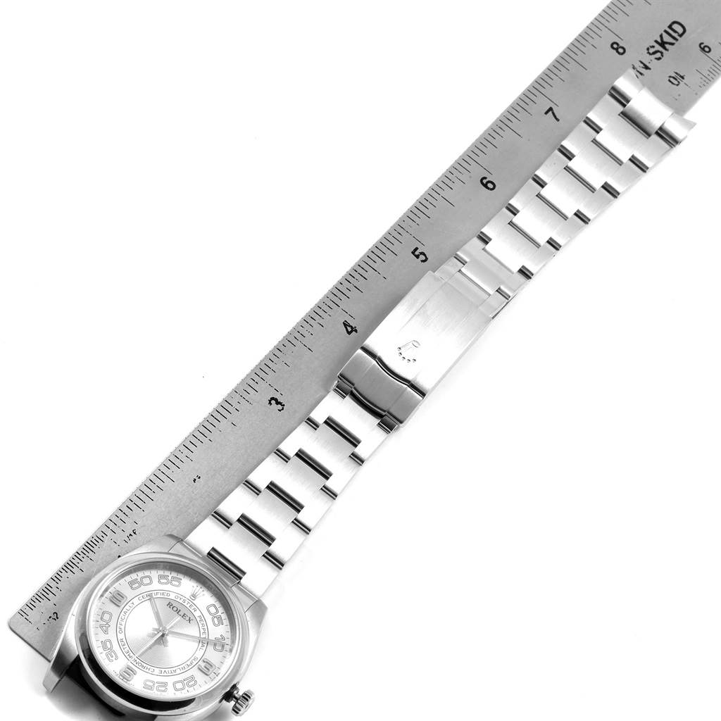 The image shows a Rolex Oyster Perpetual 116000 Men
s Stainless Steel Silver Dial 116000 Men
s Stainless Steel Silver Dial watch laid flat with its bracelet extended, measured against a ruler.