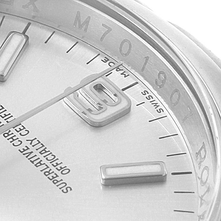 The image shows a close-up of the dial and rehaut of a Rolex Oyster Perpetual 116000 Men
s Stainless Steel Silver Dial 116000 Men
s Stainless Steel Silver Dial watch, including the hour markers and part of a number.