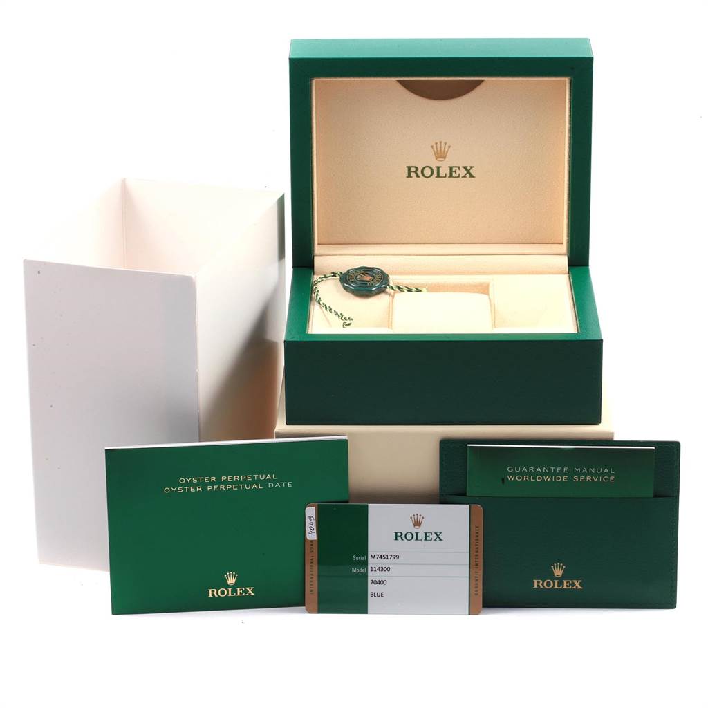 The image shows the packaging, guarantee manual, and warranty card for a Rolex Oyster Perpetual 114300 Men
s Stainless Steel Blue Dial 114300 Men
s Stainless Steel Blue Dial watch.