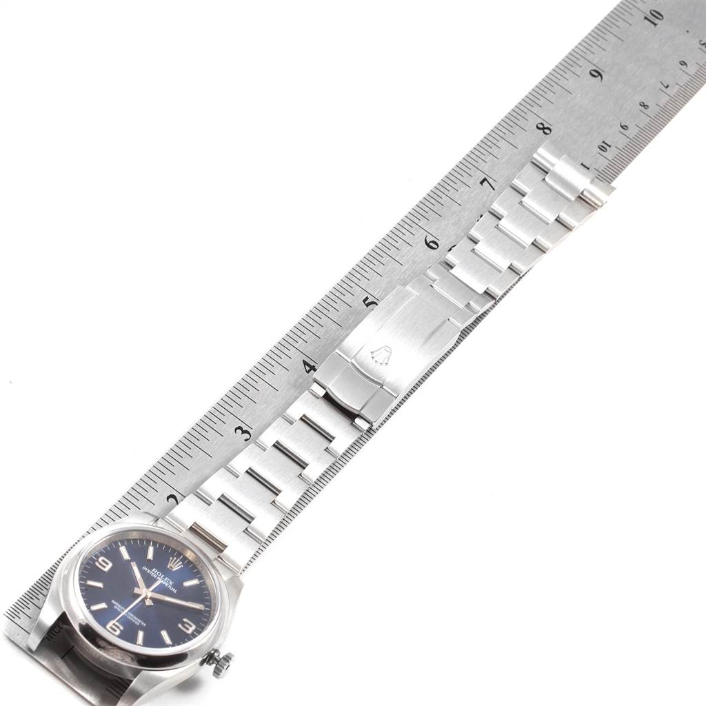 The image shows a side view of a Rolex Oyster Perpetual 116000 Men
s Stainless Steel Blue Dial 116000 Men
s Stainless Steel Blue Dial watch with its bracelet extended and aligned with a ruler for measurement.