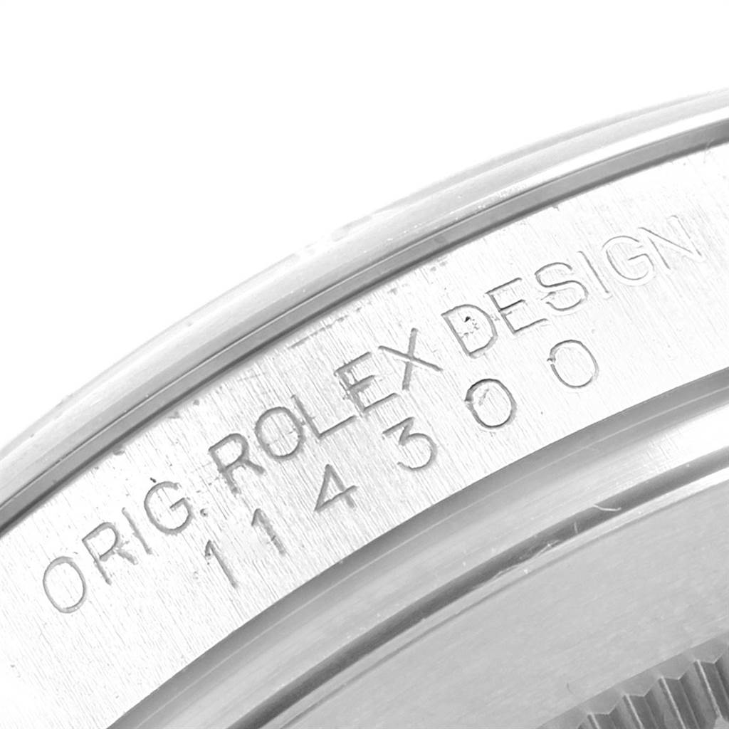 This image shows an engraved side view of the bezel of a Rolex Oyster Perpetual 114300 Men
s Stainless Steel Blue Dial 114300 Men
s Stainless Steel Blue Dial watch, displaying "ROLEX DESIGN" and the model number.