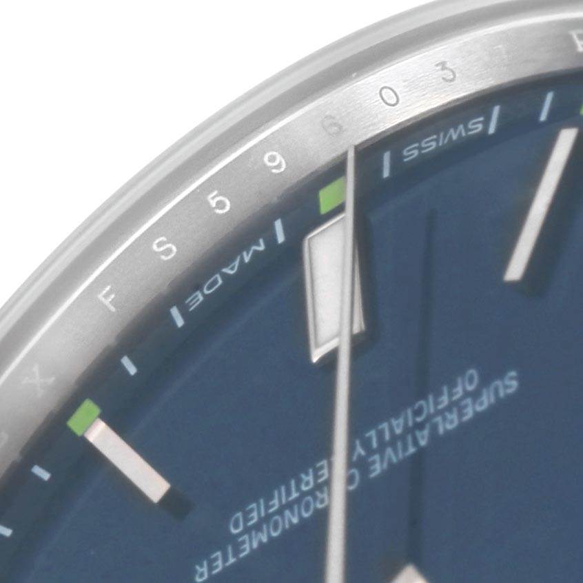 The image shows a close-up of the dial and hour markers of a Rolex Oyster Perpetual 114300 Men
s Stainless Steel Blue Dial 114300 Men
s Stainless Steel Blue Dial watch, focusing on the 5 and 6-hour markers.