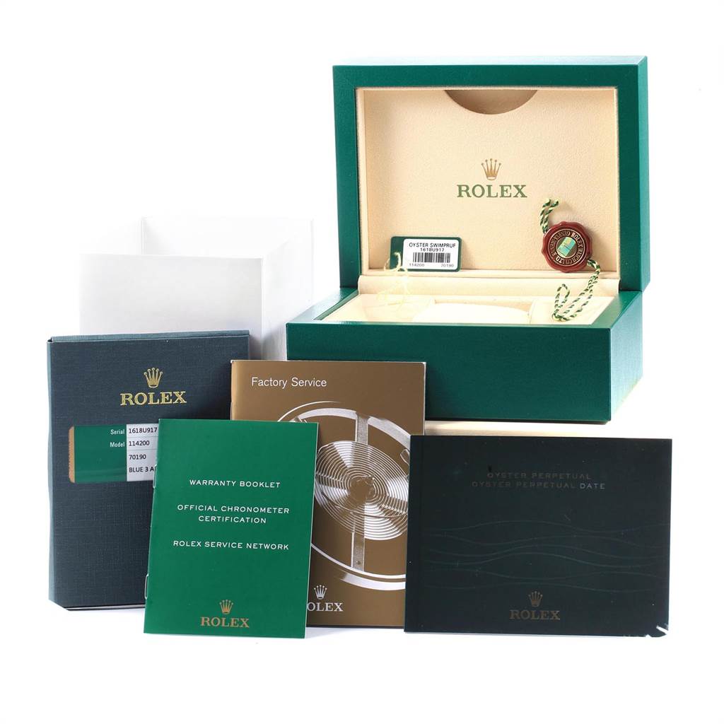 The image shows the Rolex Oyster Perpetual 114200 Men
s Stainless Steel Blue Dial 114200 Men
s Stainless Steel Blue Dial packaging, including the box, warranty booklet, factory service booklet, and other documents.