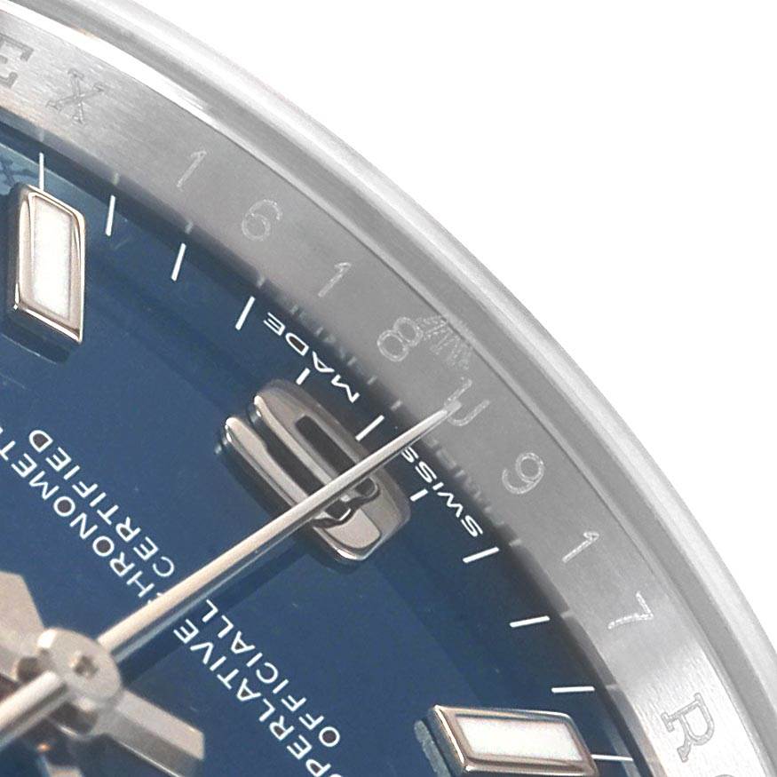 This close-up of a Rolex Oyster Perpetual 114200 Men
s Stainless Steel Blue Dial 114200 Men
s Stainless Steel Blue Dial watch shows the dial, hour markers, and part of the hands.