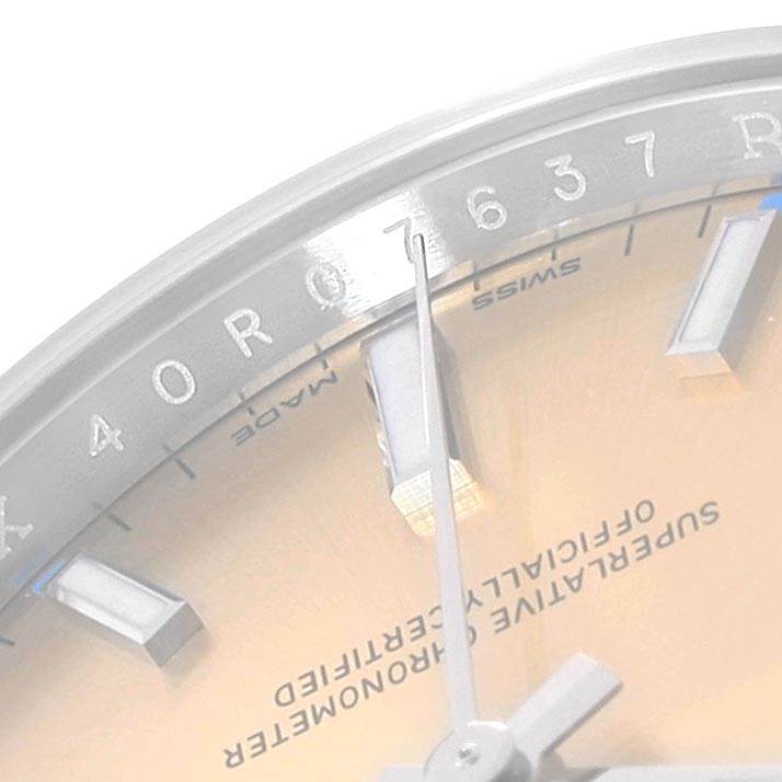 This close-up image of the Rolex Oyster Perpetual 114200 Men
s Stainless Steel Champagne Dial 114200 Men
s Stainless Steel Champagne Dial watch shows the dial, hour markers, and part of the hands.