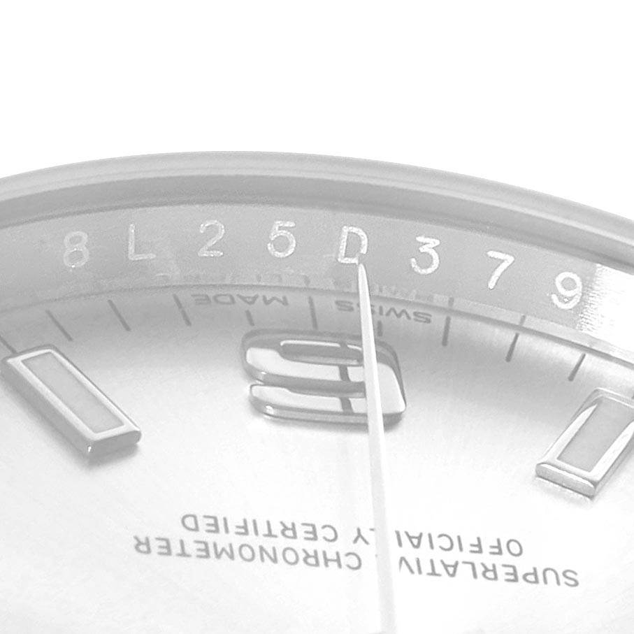 The image shows a close-up of the dial and part of the bezel of a Rolex Oyster Perpetual 114200 Men
s Stainless Steel Silver Dial 114200 Men
s Stainless Steel Silver Dial watch, highlighting numerals and text details.