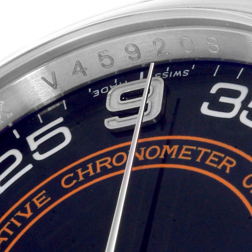 The image shows a close-up view of the Rolex Oyster Perpetual 116000 Men
s Stainless Steel Black Dial 116000 Men
s Stainless Steel Black Dial watch, focusing on its dial and part of its bezel with engraved alphanumeric codes.